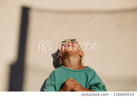 Smiling blond child wearing round sunglasses in warm sunlight. Smiling blond child wearing round sunglasses in warm sunlight. 138809419