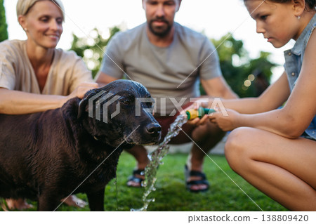 Parents and child cooling dog with water on sunny day. Parents and child cooling dog with water on sunny day. 138809420