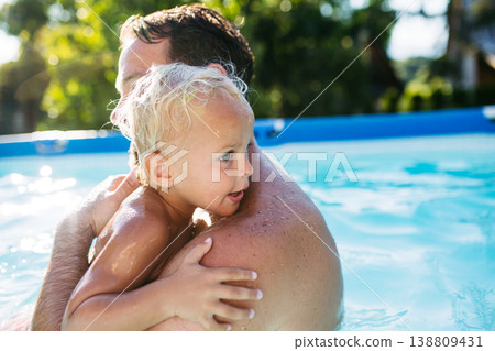 Little boy splashing and playing in pool with dad. 138809431