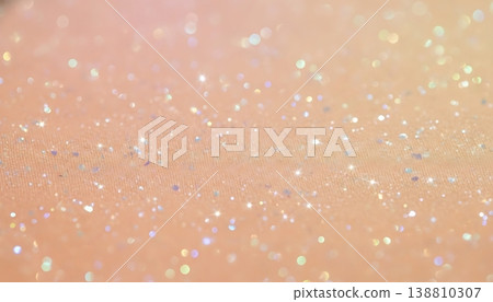 Close-up view of shimmering glitter particles on a soft peach fabric background, showcasing a sparkling texture ideal for creative projects and design applications 138810307