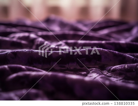 Close-up view of textured purple fabric with intricate folds and patterns, showcasing a rich, luxurious appearance suitable for upholstery or fashion design 138810335