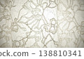 Intricate white lace fabric with floral patterns and beaded details, showcasing delicate craftsmanship and texture suitable for fashion or home decor applications 138810341
