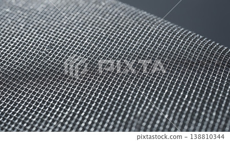 Close-up view of metallic wire mesh fabric showcasing intricate grid pattern and fine details, suitable for various industrial and architectural applications 138810344