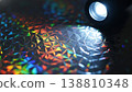 Close-up of flashlight illuminating textured holographic surface with colorful reflections and geometric patterns, showcasing intricate details and light interaction 138810348
