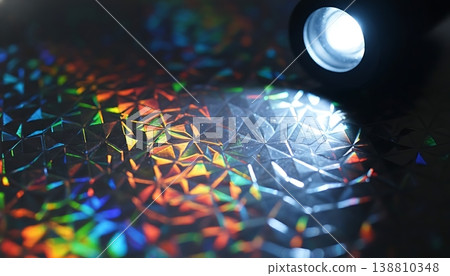 Close-up of flashlight illuminating textured holographic surface with colorful reflections and geometric patterns, showcasing intricate details and light interaction Close-up of flashlight illuminating textured holographic surface with colorful reflections and geometric patterns, showcasing intricate details and light interaction 138810348
