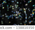 Close-up of colorful sequins on black fabric, showcasing a shimmering texture with various sizes and reflections, ideal for fashion or textile design applications 138810350
