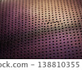 Close-up view of textured purple leather material with perforated holes, showcasing the intricate design and craftsmanship of the fabric surface 138810355