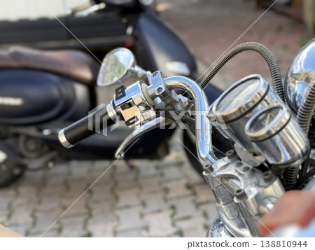Motorcycle handlebar with chrome details on a paved street background 138810944