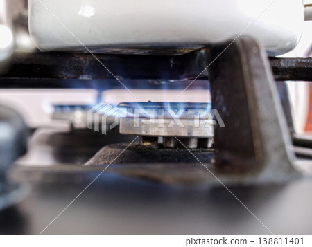 Gas burner. Gas is burning under a white kettle, a focus on the background Gas burner. Gas is burning under a white kettle, a focus on the background 138811401