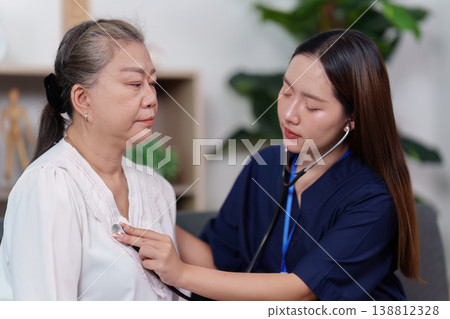 Nurse checking elderly woman's heartbeat with stethoscope 138812328