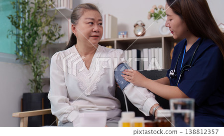 Nurse measuring blood pressure of elderly woman at home 138812357