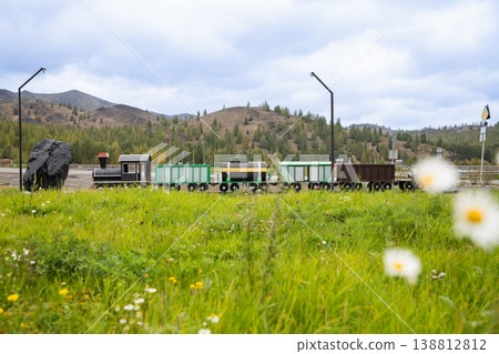 Old Soviet toy train with carriages, realistic model in the open air against the backdrop of mountains. Nostalgic memory, symbol of industry Old Soviet toy train with carriages, realistic model in the open air against the backdrop of mountains. Nostalgic memory, symbol of industry 138812812