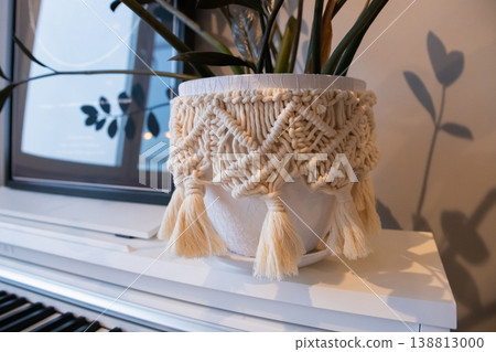 Decorative pot with zamioculcas plant decorated with diy macrame on piano with green plant inside in cozy interior Decorative pot with zamioculcas plant decorated with diy macrame on piano with green plant inside in cozy interior 138813000