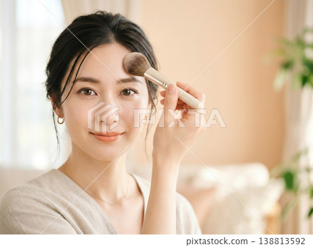 一張日本女性在桃色背景前撲粉的美麗肖像。 一張日本女性在桃色背景前撲粉的美麗肖像。 138813592