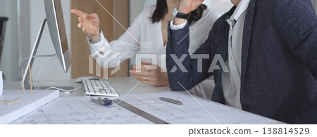 Architects collaborating on architectural project, discussing blueprints and design models on office table. Business and architecture concept Architects collaborating on architectural project, discussing blueprints and design models on office table. Business and architecture concept 138814529