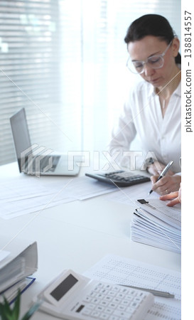 Businesswoman hands calculating taxes and preparing financial documents at office desk, reviewing budget and audit reports. Audit and taxes concept Businesswoman hands calculating taxes and preparing financial documents at office desk, reviewing budget and audit reports. Audit and taxes concept 138814557