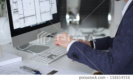Professional architect drafting blueprints at a desk, holding a compass, focusing on structural plans and urban design. Business and architecture concept Professional architect drafting blueprints at a desk, holding a compass, focusing on structural plans and urban design. Business and architecture concept 138814558