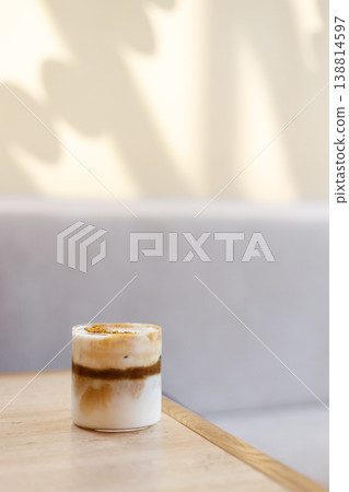 Cup of creation coffee drink and milk foam decorated with Osmanthus flower on wooden table by the window. 138814597