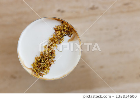Cup of creation coffee drink and milk foam decorated with Osmanthus flower on wooden table by the window. 138814600