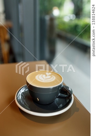 Cup of hot milk latte coffee on table by the window. Cup of hot milk latte coffee on table by the window. 138814624