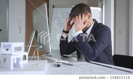 Frustrated man suffering from stress and exhaustion at work, holding his head, feeling overwhelmed by professional pressure. Business and architecture concept Frustrated man suffering from stress and exhaustion at work, holding his head, feeling overwhelmed by professional pressure. Business and architecture concept 138815118