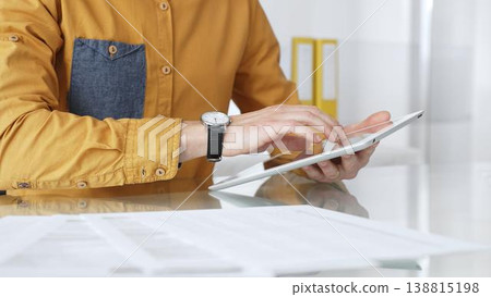 Person using a digital tablet for business at desk, navigating online content or browsing documents. Audit and taxes in business 138815198