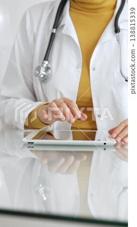 Doctor using tablet computer for digital health data, patient records, and medical application in clinic. Medicine, healthcare and science concept 138815339