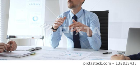 Business professional presenting financial strategy during corporate meeting with colleagues, analyzing charts and discussing data for growth and success planning 138815435