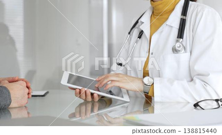 Doctor consulting patient using digital tablet, explaining medical information during modern healthcare appointment. Medicine, healthcare and science concept Doctor consulting patient using digital tablet, explaining medical information during modern healthcare appointment. Medicine, healthcare and science concept 138815440