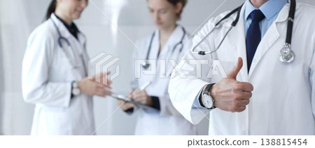 Doctor giving thumbs up sign for medical approval while standing with health practitioners, symbolizing trust in healthcare, patient well being, and successful treatment Doctor giving thumbs up sign for medical approval while standing with health practitioners, symbolizing trust in healthcare, patient well being, and successful treatment 138815454