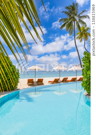 Luxury tropical resort pool sunbeds umbrella vertical composition turquoise water palm trees sunny summer vacation travel tourism wallpaper paradise destination 138815969