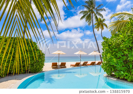 Luxury tropical resort poolside scene with sunbeds umbrellas palm trees turquoise water relaxing summer vacation travel destination 138815970