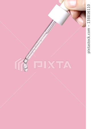 Pipette with serum in hand. Drips drop isolated on pink background, vertical 138816110