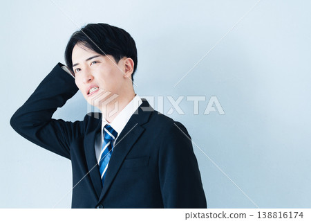 一個身穿西裝的年輕男子雙手抱頭。 138816174