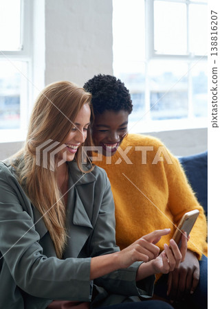 Happy, social media and women with a phone on a work sofa for communication, notification or a chat. Smile, digital and diversity with friends reading from a mobile app, contact or email together Happy, social media and women with a phone on a work sofa for communication, notification or a chat. Smile, digital and diversity with friends reading from a mobile app, contact or email together 138816207