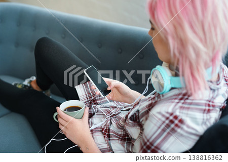 Relax, coffee and a woman with a phone for music, social media or communication on the sofa. Contact, tech and a punk girl with a drink and a mobile for streaming a podcast or audio on the couch Relax, coffee and a woman with a phone for music, social media or communication on the sofa. Contact, tech and a punk girl with a drink and a mobile for streaming a podcast or audio on the couch 138816362