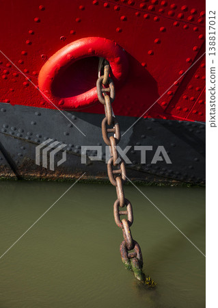 Red boat weighing anchor in deep green water Red boat weighing anchor in deep green water 138817012