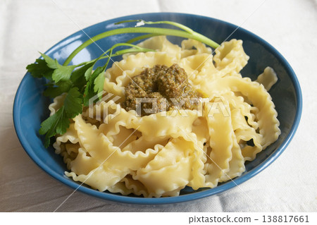 Italian mafaldine pasta with basil pesto and fresh parsley in blue bowl Italian mafaldine pasta with basil pesto and fresh parsley in blue bowl 138817661