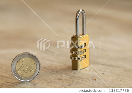 Two coin and brass combination padlock on wooden surface Two coin and brass combination padlock on wooden surface 138817786