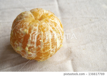 Peeled whole mandarin orange on rustic white linen background Peeled whole mandarin orange on rustic white linen background 138817789