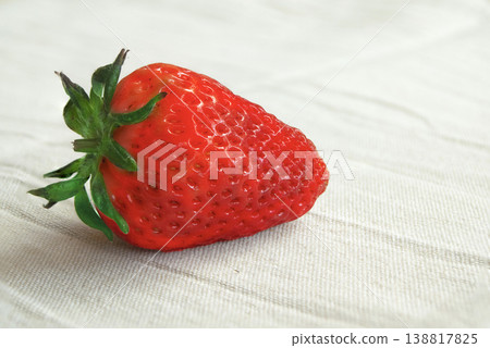 Single fresh organic strawberry on white linen background Single fresh organic strawberry on white linen background 138817825