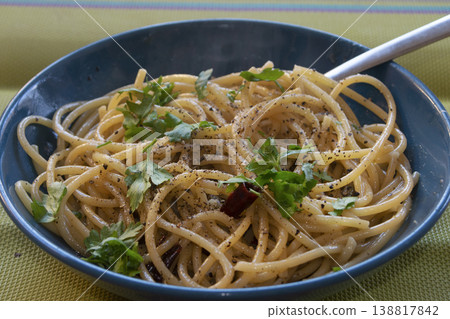 Spaghetti aglio olio e peperoncino with fresh parsley in blue bowl Spaghetti aglio olio e peperoncino with fresh parsley in blue bowl 138817842