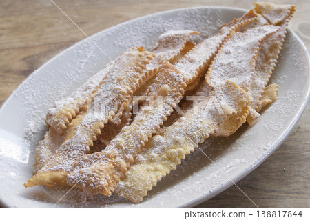 Italian Carnival fritters chiacchiere with powdered sugar on white plate Italian Carnival fritters chiacchiere with powdered sugar on white plate 138817844