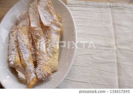 Italian Carnival fritters chiacchiere with powdered sugar on white plate Italian Carnival fritters chiacchiere with powdered sugar on white plate 138817845