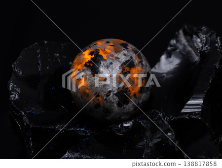 Macro View of Polished Oranges and Black Stone Sphere Resting on Jagged Obsidian Glass Fragments 138817858