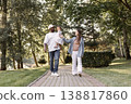 Happy interracial family walking in park on sunny summer day. Father holding little daughter in arms while mother walks. Warm lifestyle, parenting outdoors. People walking 138817860