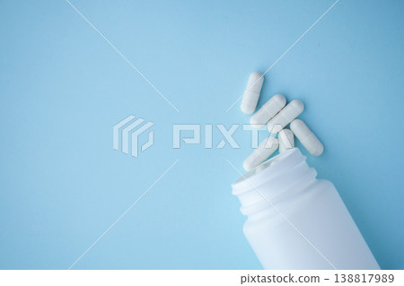 medicine pills capsule spilling out of bottle on blue background medicine pills capsule spilling out of bottle on blue background 138817989