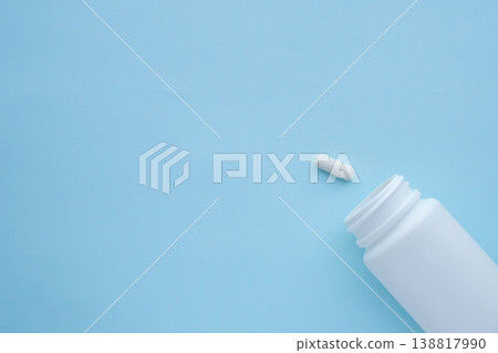 medicine pills capsule spilling out of bottle on blue background medicine pills capsule spilling out of bottle on blue background 138817990