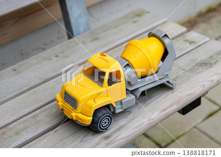 Yellow toy cement mixer truck on wooden bench with blurred rustic background Yellow toy cement mixer truck on wooden bench with blurred rustic background 138818171