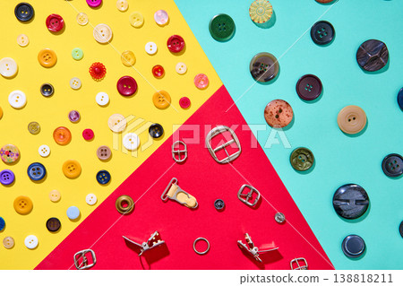 Colorful sewing accessories composition on geometric background, buttons and metal buckles Colorful sewing accessories composition on geometric background, buttons and metal buckles 138818211